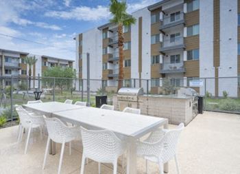 a patio with tables and chairs and an apartment building in the background